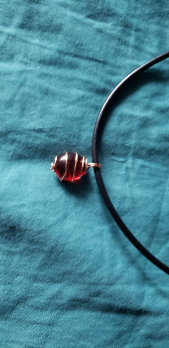 Red glass stone pendant wrapped in copper wire.